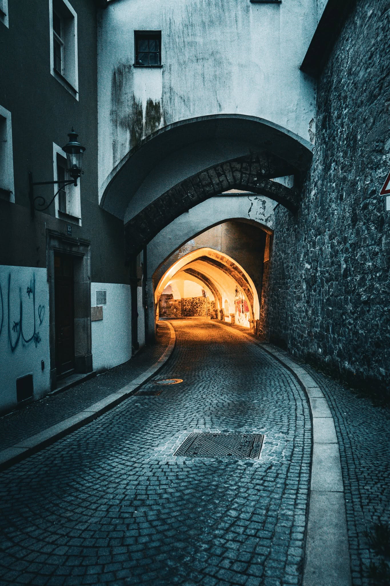 Passau Altstadt-Gasse — historische Steinbögen und Kopfsteinpflastergasse bei Nacht, warm beleuchtet