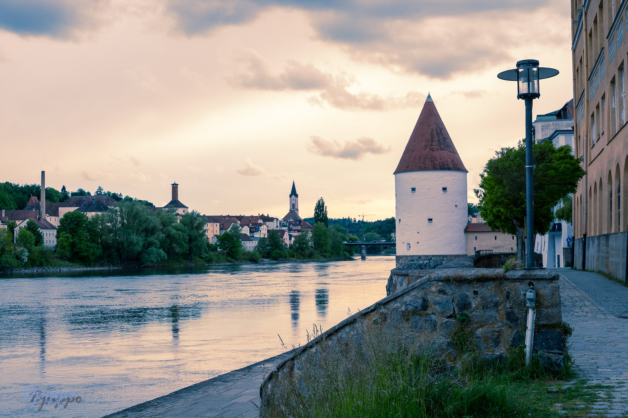 Passau Schaiblingsturm am Ilzpromenade — runder Turm mit rotem Kegeldach am Flussufer bei Abenddämmerung