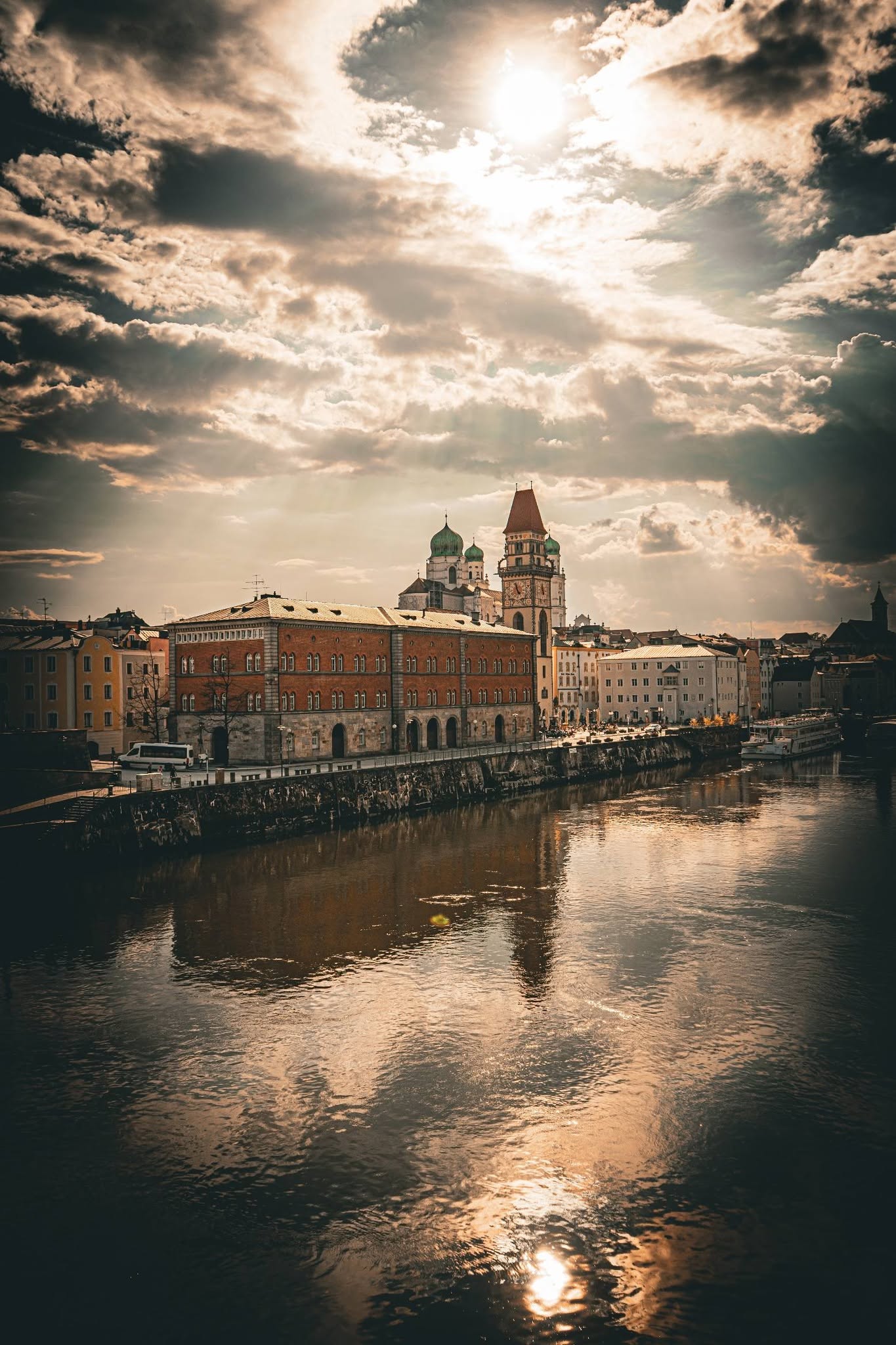 Passau dramatischer Sonnenuntergang — goldenes Licht über der Donau mit dem Dom und historischen Gebäuden am Ufer