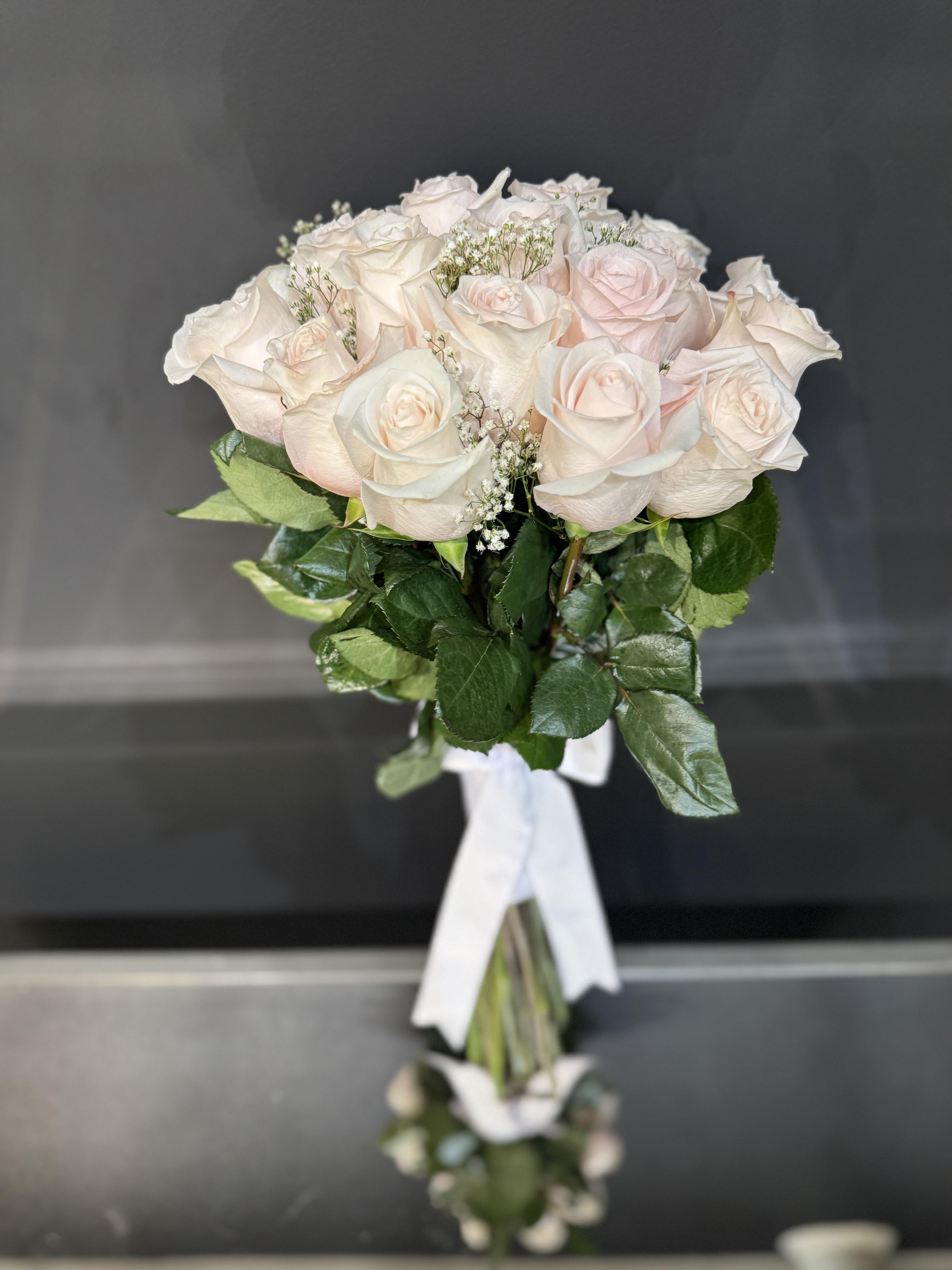 Poetic white and blush arrangement with delicate ranunculus and flowing ribbon