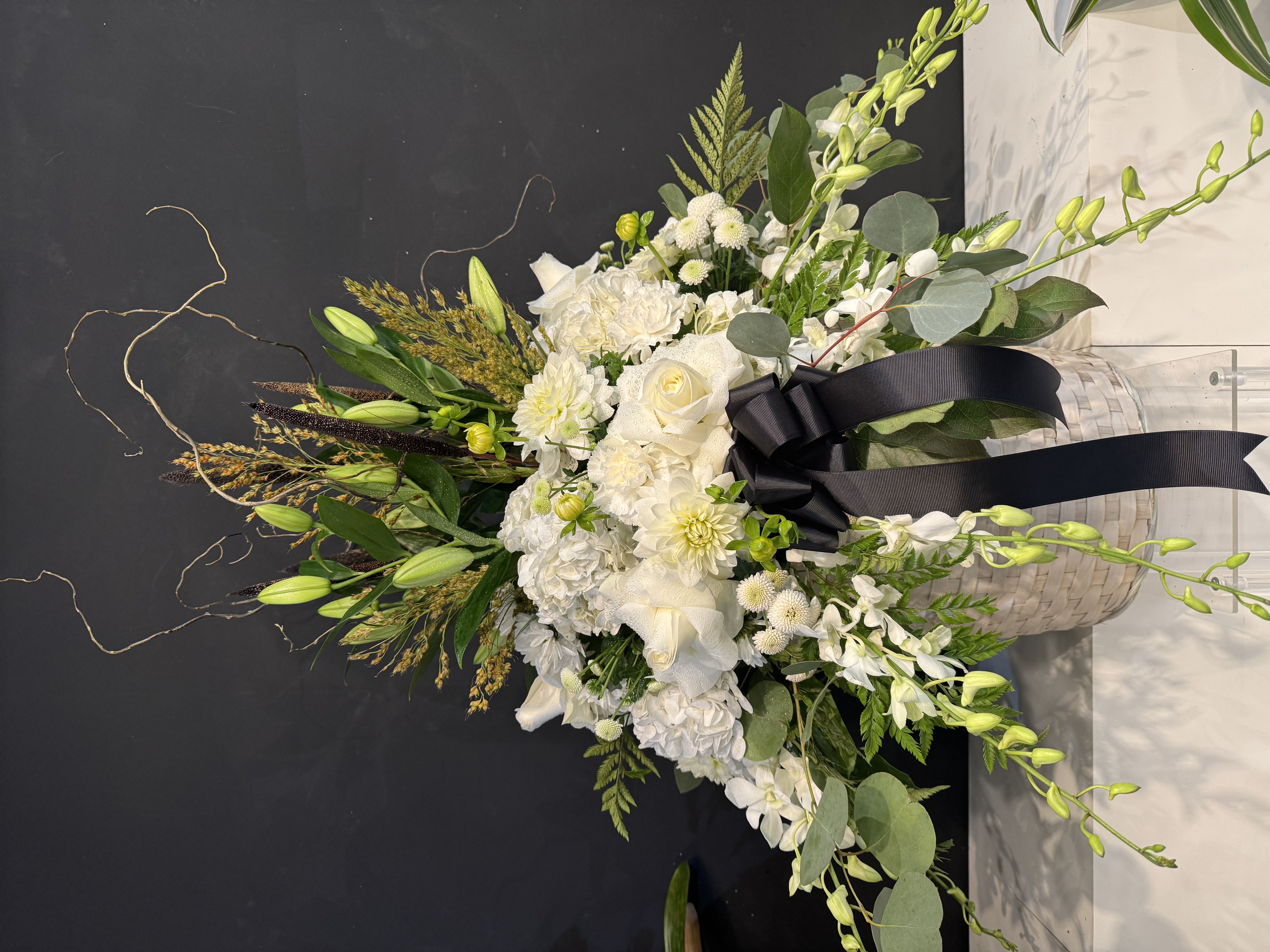 White carnation and fern standing spray with satin ribbon accents