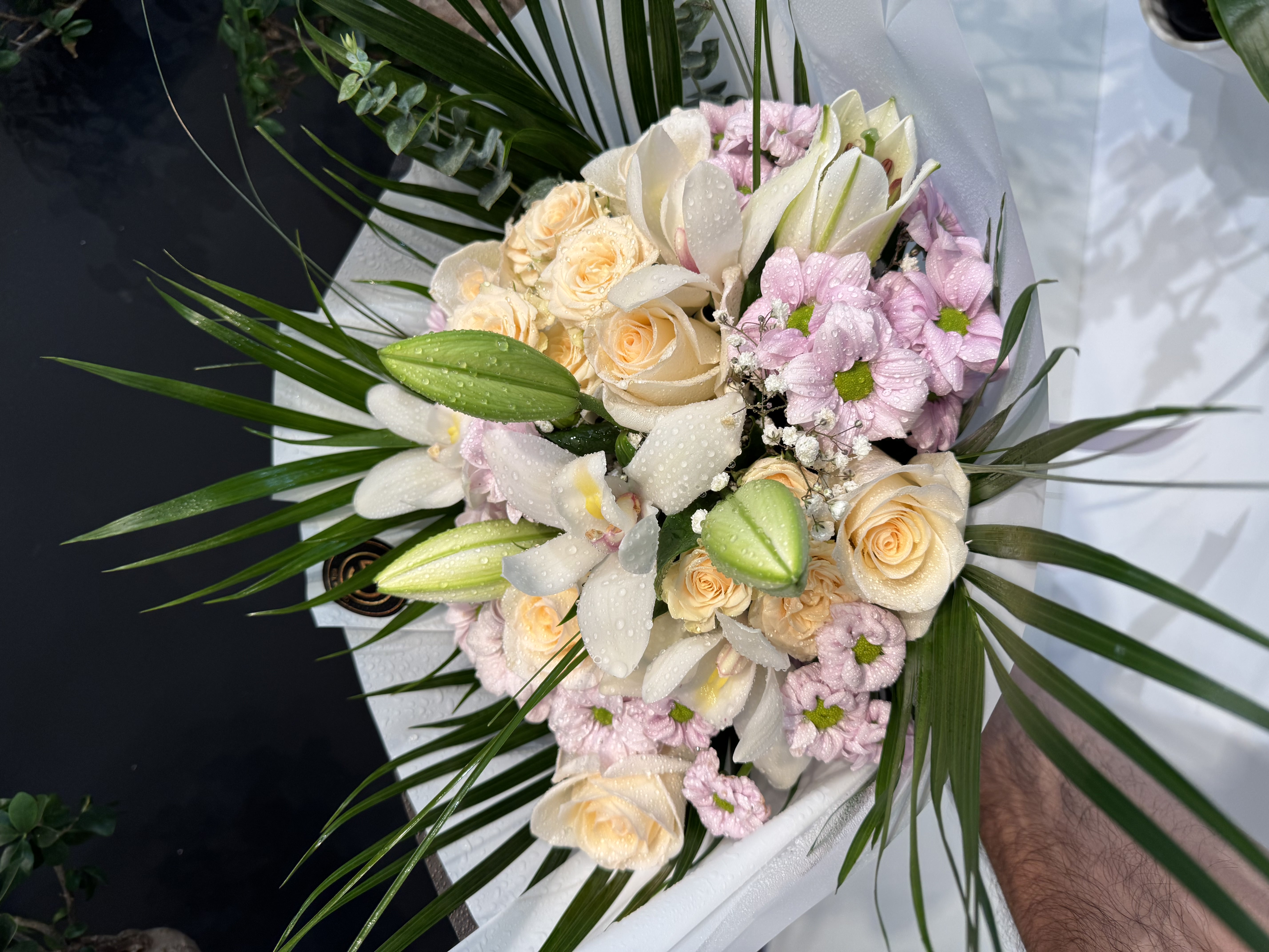 Orchid and rose arrangement with tropical foliage