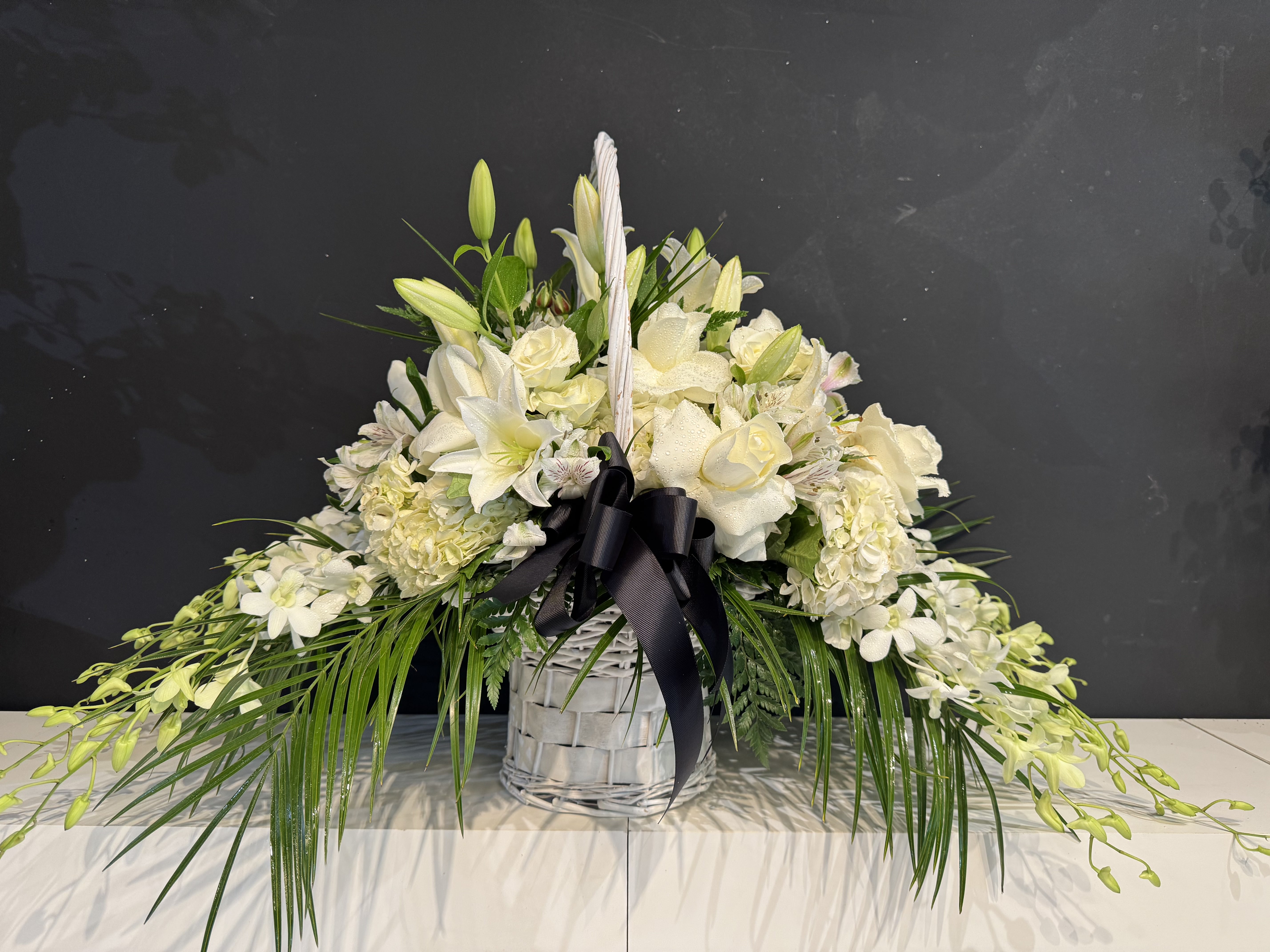 White rose and eucalyptus sympathy basket with satin bow