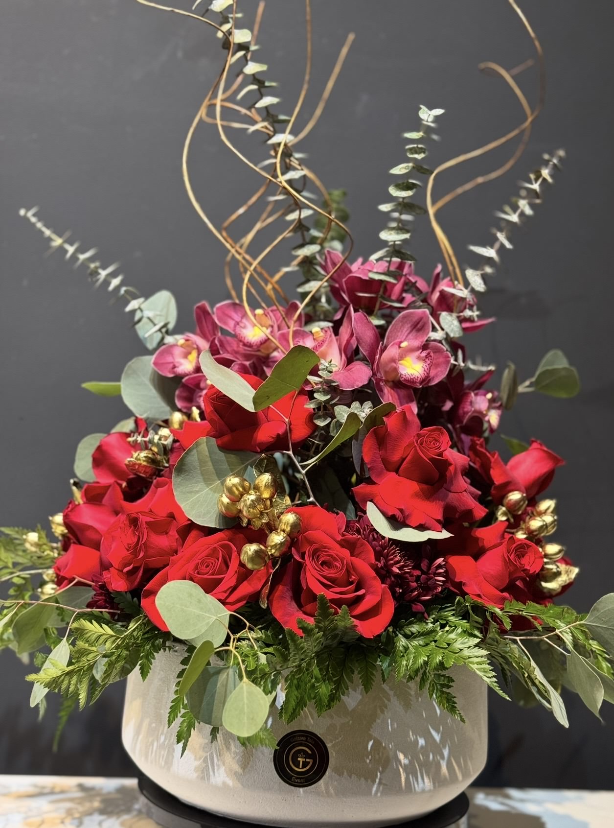 Elegant deep-toned arrangement with rich burgundy and gold — a stunning centerpiece for Christmas Eve