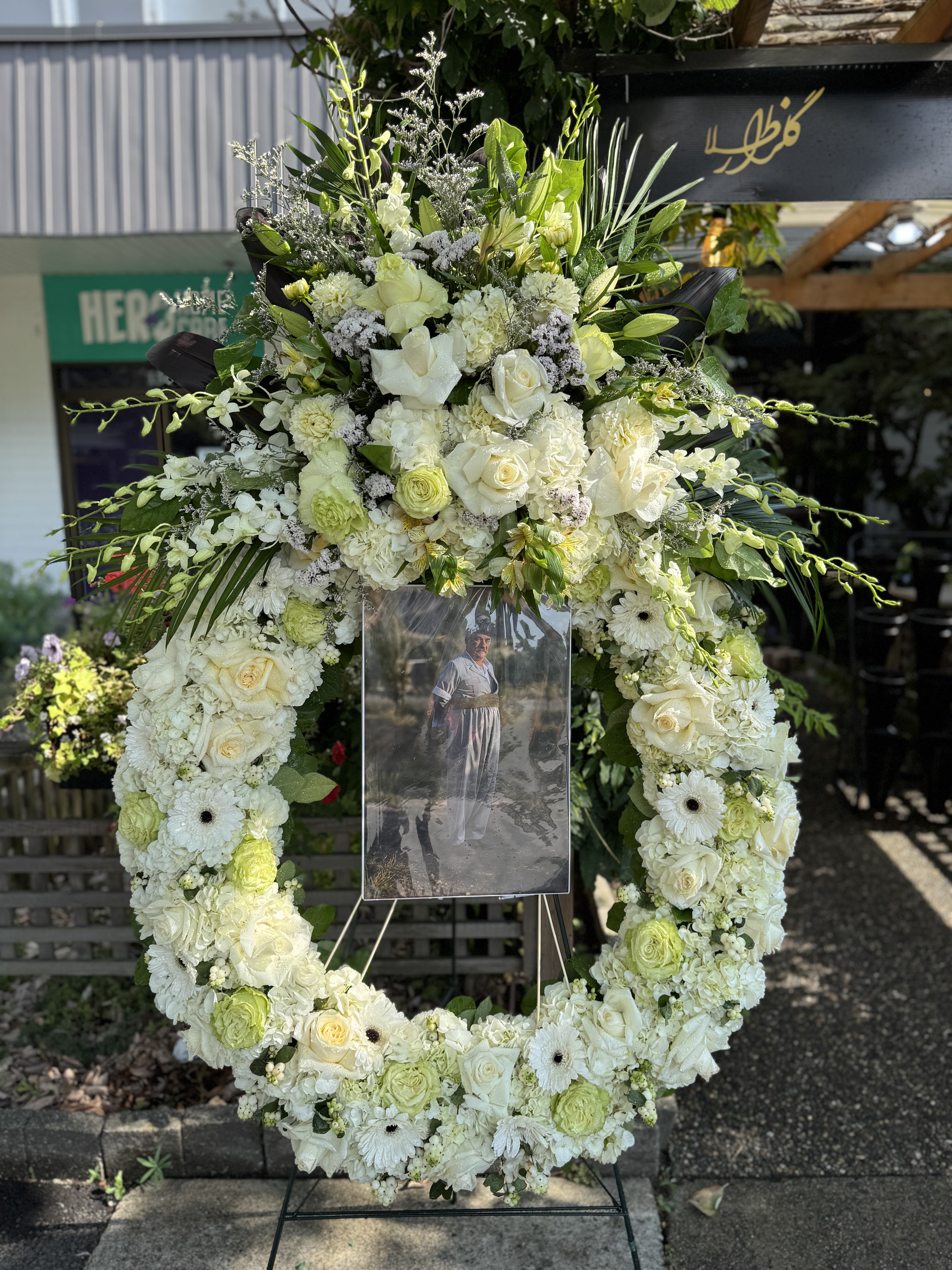 White rose and baby breath half-casket spray with fern accents