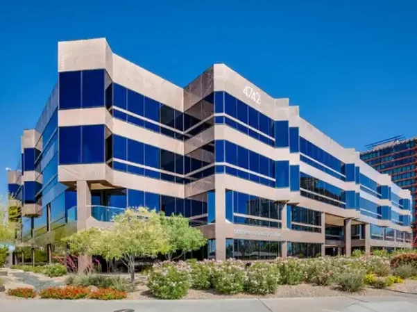Fast Passport Center office building in Phoenix, Arizona — modern multi-story glass and stone professional building with blue reflective windows at 4742 N 24th St in the Camelback East corridor, desert landscaping in foreground, clear blue Arizona sky