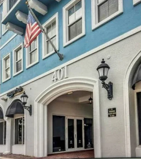 Fast Passport Center office at 401 W Atlantic Ave in Delray Beach, Florida — turquoise and white building with American flag above the entrance