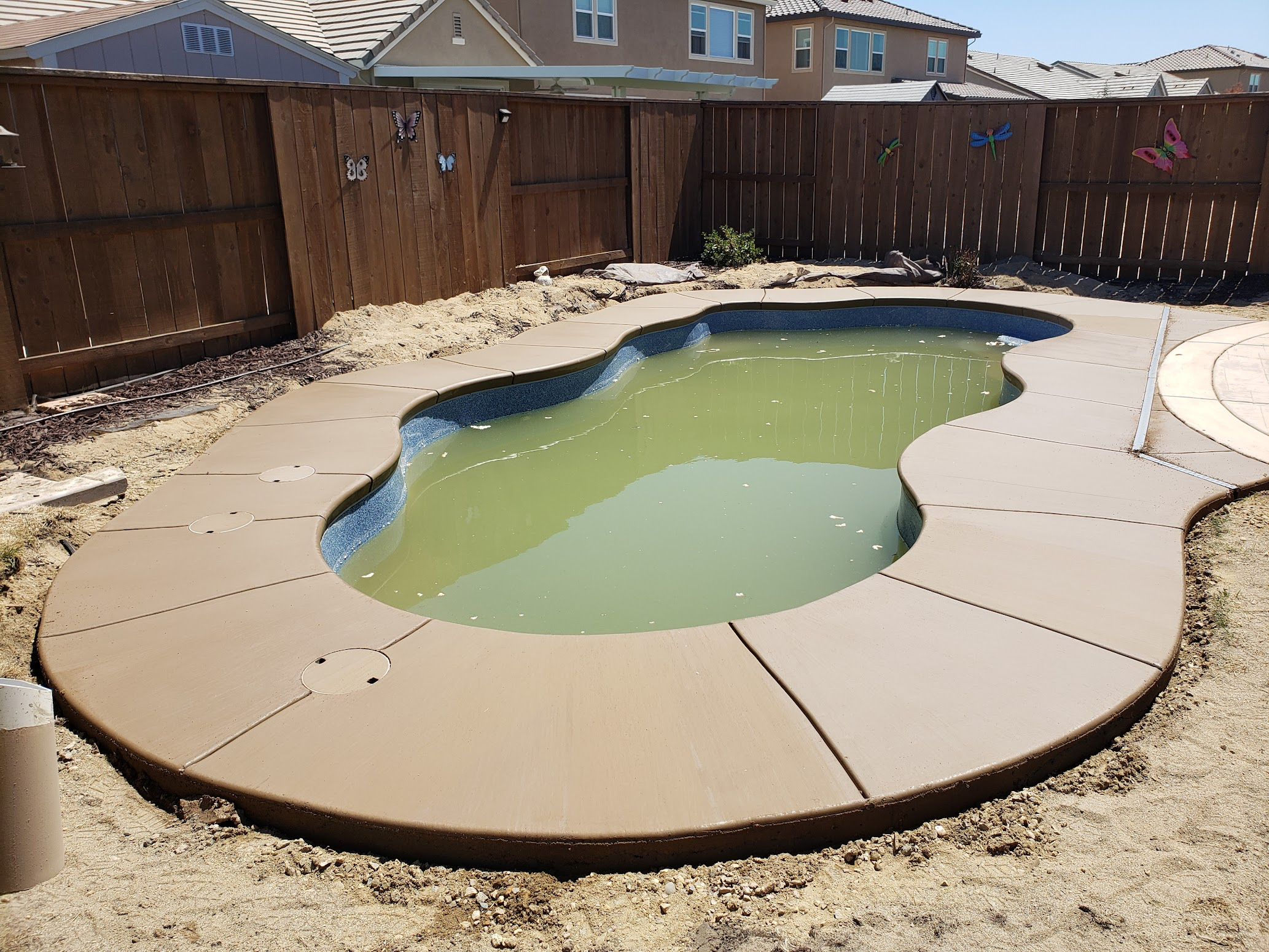 Freshly poured concrete pool deck around custom pool in Modesto, CA