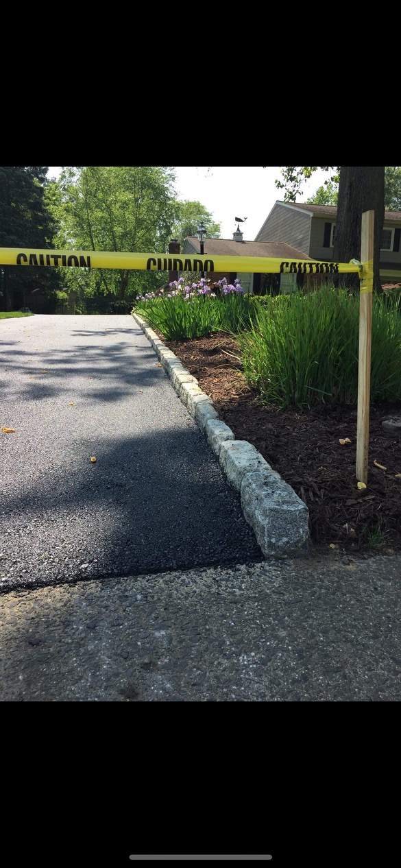 Newly paved residential driveway with fresh asphalt and landscaping