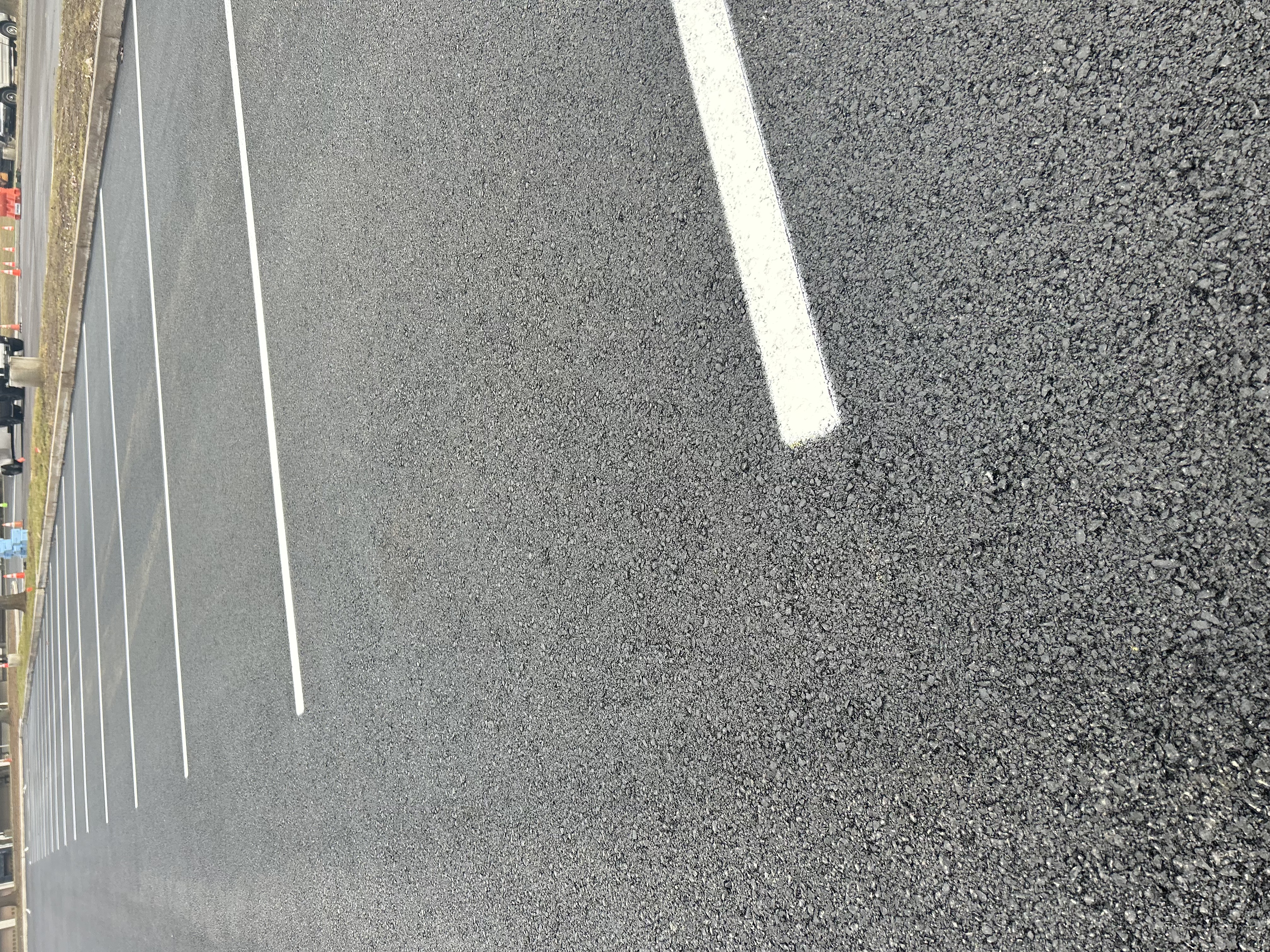 Fresh traffic paint application showing bright line markings on paved commercial surface