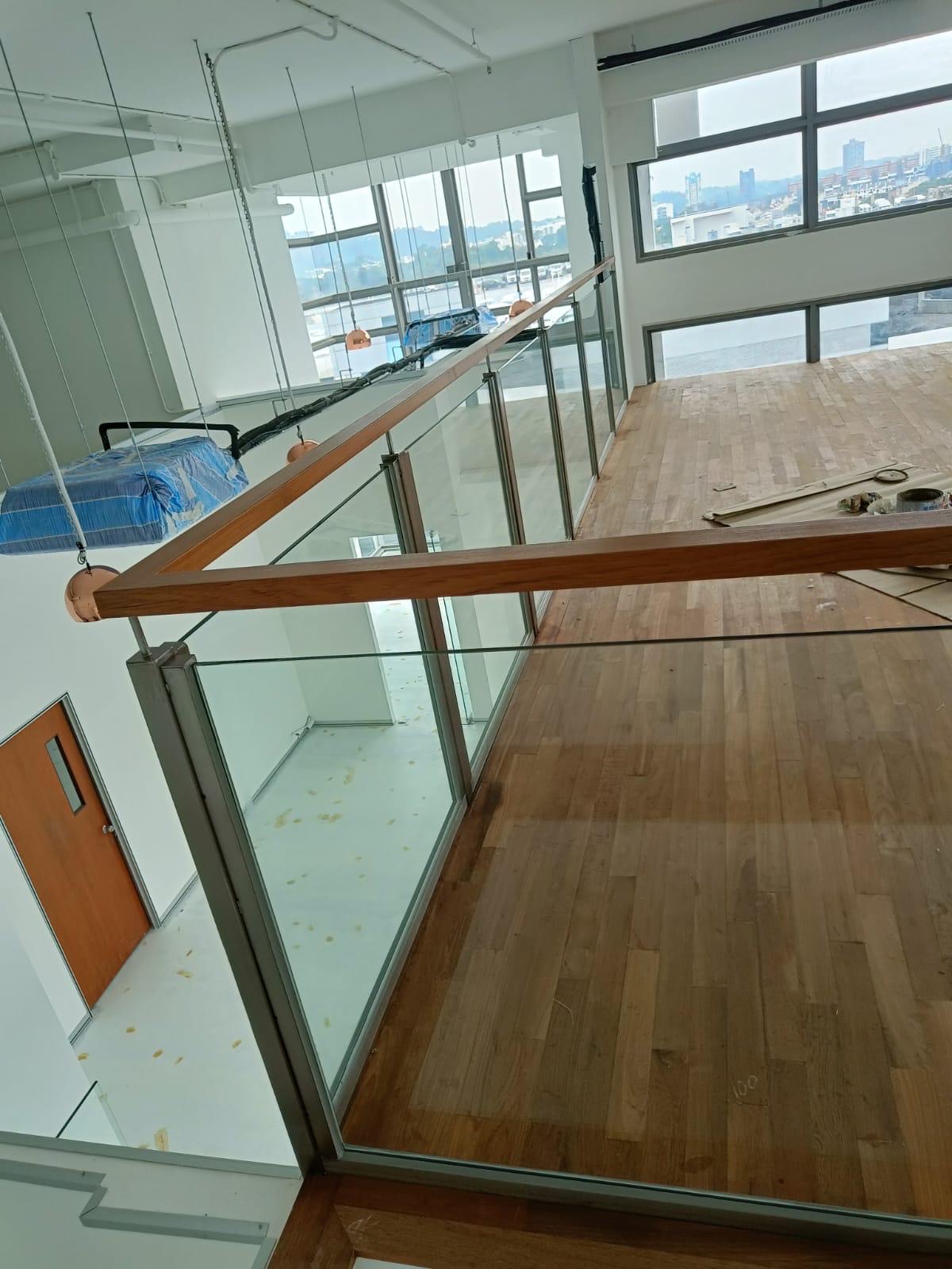 Close-up of round wooden handrail mounted on 13.52mm laminated glass panel with stainless steel bracket