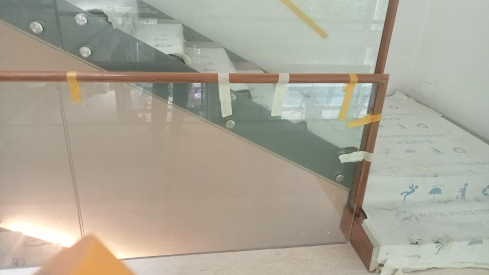 Wide angle view of glass railing with wooden handrail along staircase landing in Bukit Timah bungalow