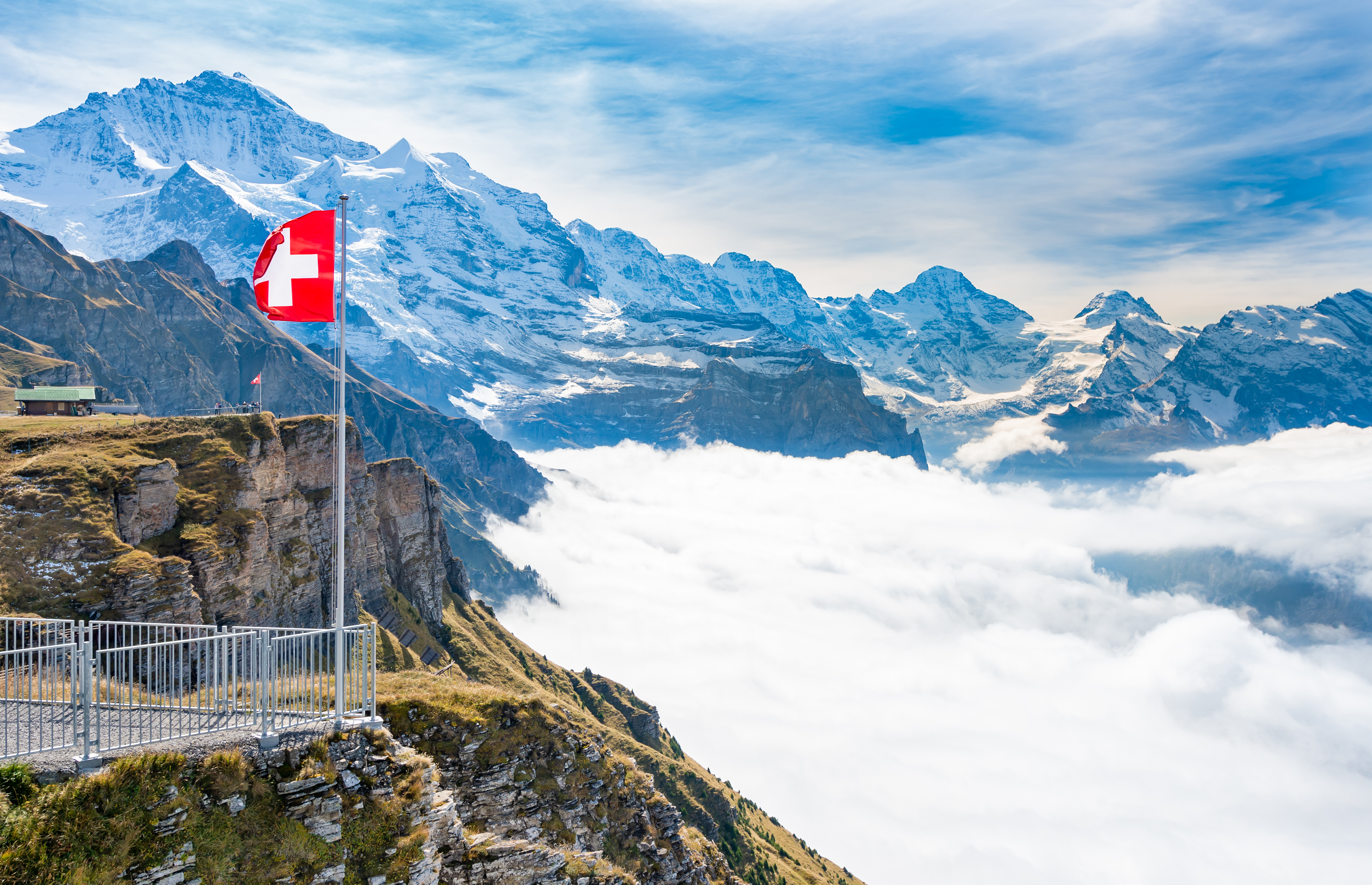 Drapeau suisse flottant au-dessus d'une mer de nuages