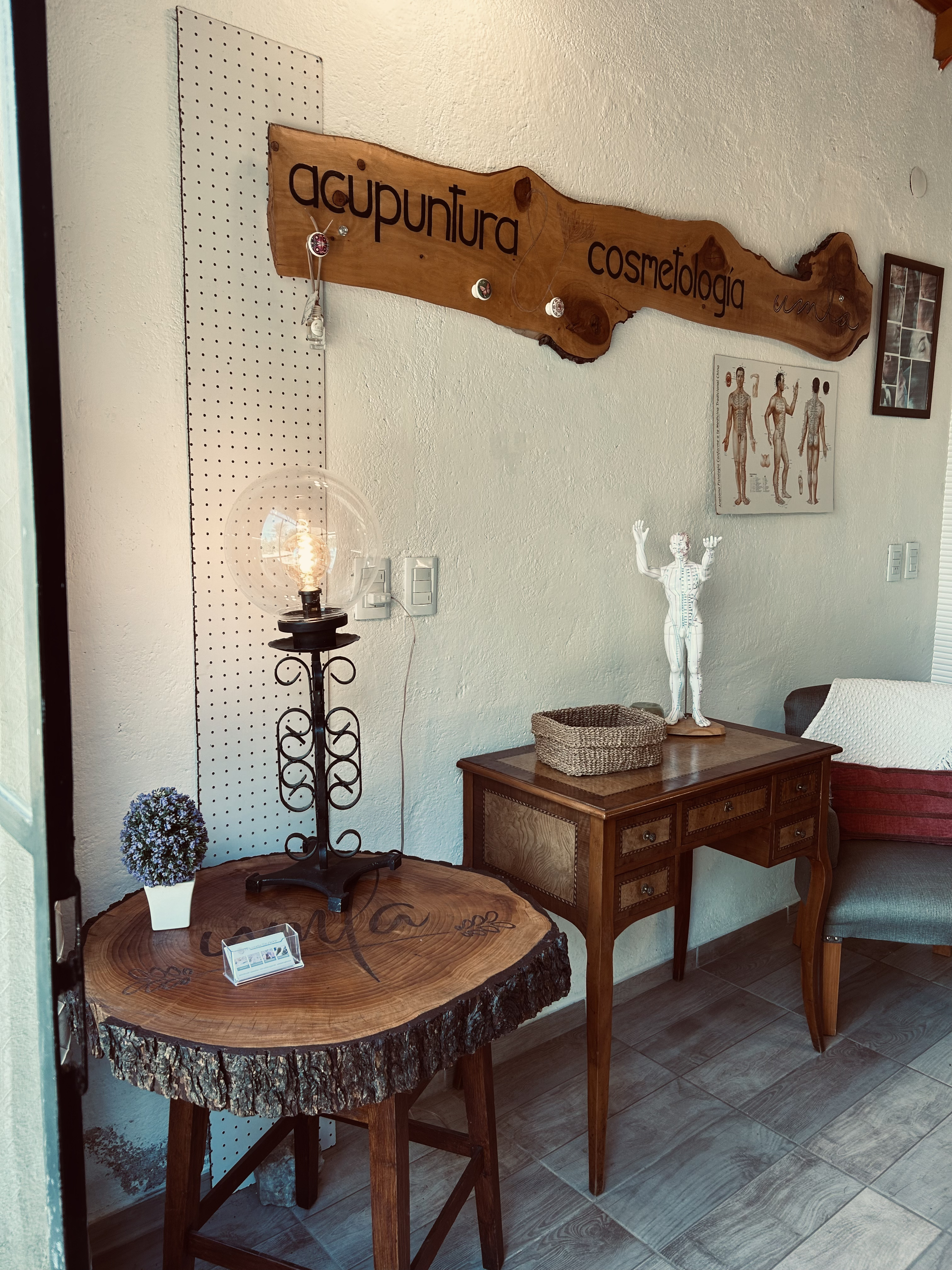 Consultorio Umla Terapias – vista del cartel de acupuntura y cosmetología con mesa de tronco